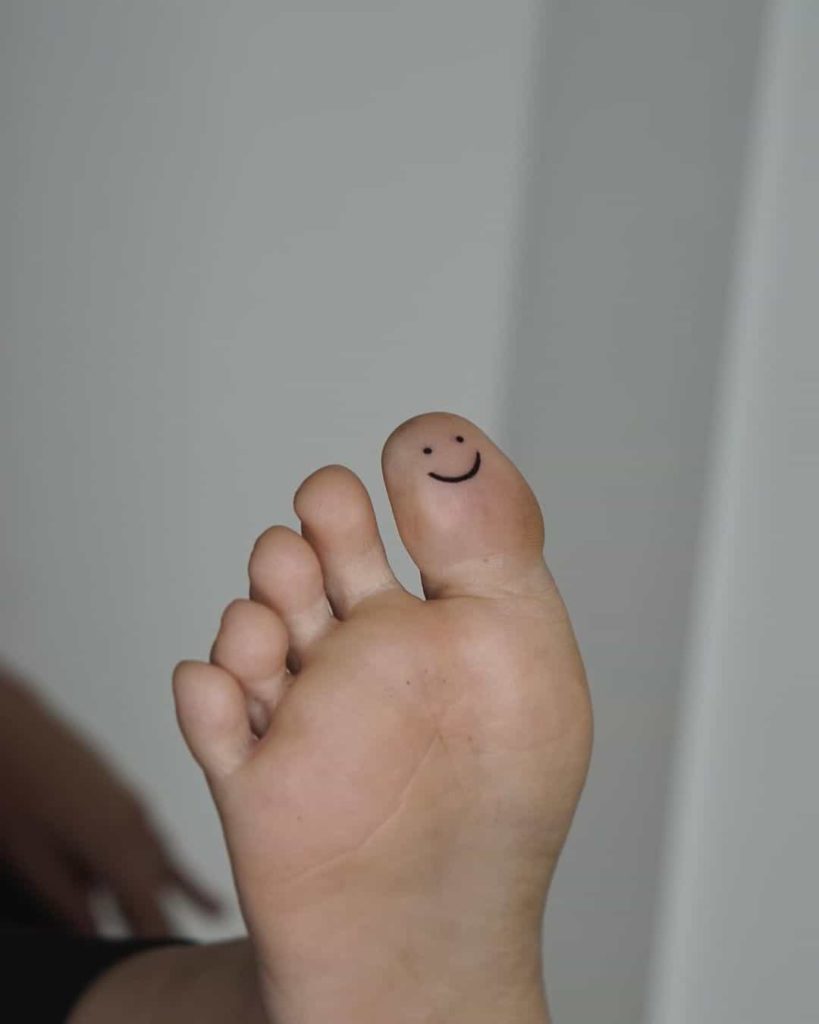 Smiley face tattoo on toe